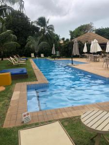 ein Pool in einem Resort mit Liegestühlen und Sonnenschirmen in der Unterkunft Apartamento 2 suítes em condomínio de luxo no centro in Praia do Forte