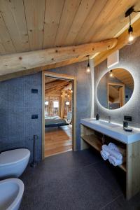 a bathroom with a sink and a toilet and a mirror at Agriturismo Botondoro in San Nicolò di Comelico