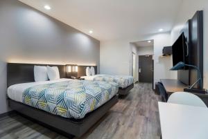 a hotel room with two beds and a flat screen tv at Studio 6 Katy, Tx in Katy