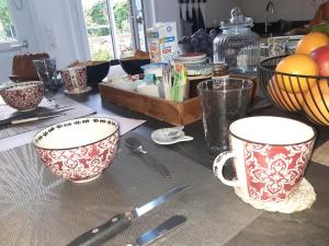 a table with two cups and utensils on it at La Caudalie in Deux-rivières