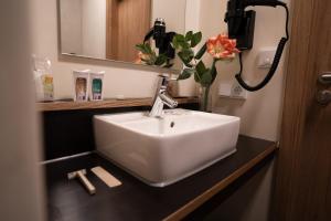 a bathroom with a white sink and a vase of flowers at Motel Q in Rottweil