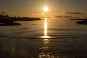 a sunset on a beach with the sun setting at Mallaig Self Catering Apartment in Mallaig