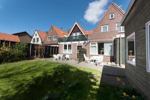een huis met een tuin met stoelen en een patio bij Egmond-vakantiewoningen in Egmond aan Zee