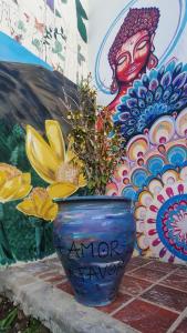 un jarrón azul con una planta delante de un mural en Roots Backpackers in 