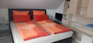 Łóżko w małym pokoju z pomarańczowymi poduszkami w obiekcie Ferienwohnung Liebscher w mieście Sehmatal