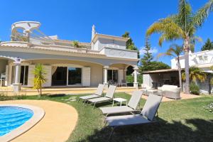 a villa with a swimming pool and lawnitures at Villa Corvo 123- Clever Details in Vilamoura
