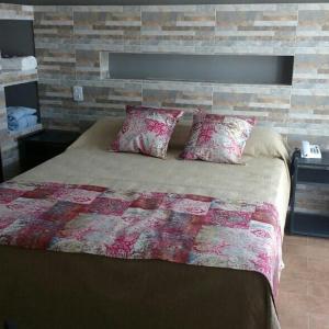 a bedroom with a large bed with a brick wall at NEFERET Habitaciones Temporarias in Corrientes
