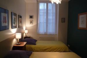 two beds in a room with a window and two lamps at Le Clos 25 in Chalon-sur-Saône
