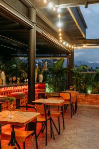 un restaurante con mesas de madera y sillas en un patio en The Somos Beats Hotel & Rooftop, en Medellín