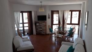 uma sala de estar com um sofá, uma mesa e cadeiras em Depto, centro, 3 de la playa, luminoso con balcón em Pinamar