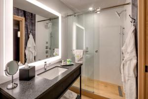 a bathroom with a shower, sink, and mirror at Peaks Hotel and Suites in Banff