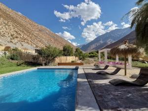 a swimming pool with two chairs and an umbrella at Reset Elqui in Alcoguaz