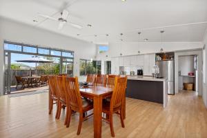 een keuken en eetkamer met een houten tafel en stoelen bij Restful Ruakaka - Ruakaka Holiday Home in Ruakaka