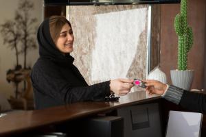 a woman is handing a man a remote control at فندق شجرة الزيتون Olive Tree Hotel in Tabuk