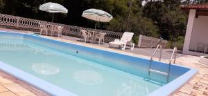 a swimming pool with chairs and umbrellas on a deck at Pousada Pedacinho do Ceu- chalé 1 in Cunha +28 photos