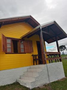 una casa amarilla con escaleras delante en Cabana Caminho das Borboletas en Bom Retiro