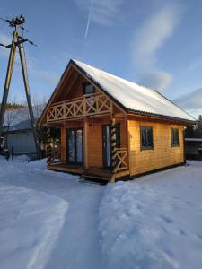 una cabaña de madera en la nieve con un molino de viento en Orawski Kąt en Zubrzyca Dolna