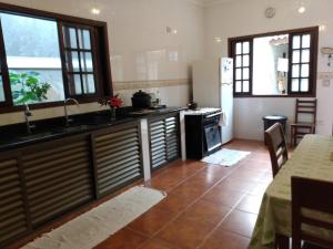 a kitchen with a sink and a refrigerator and a table at Hospedaria Namastê in Peruíbe