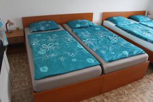 2 Betten in einem Zimmer mit blauer Bettwäsche und Kissen in der Unterkunft Chlalupa se zahradou - Chlum u Třeboně in Chlum u Třeboně