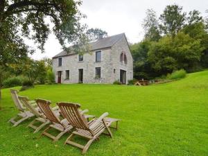 duas cadeiras sentadas na relva em frente a uma casa em Quaint Holiday Home in Robechies amid Meadows em Chimay