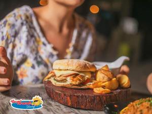 a woman holding a plate with a chicken sandwich and french fries at Casa Grande Surf in Guachaca