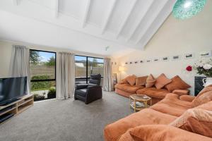 a living room with a couch and a television at Wharerata - Otaki Beach Holiday Home in Otaki Beach