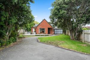 a house with a driveway and a fence at Wharerata - Otaki Beach Holiday Home in Otaki Beach