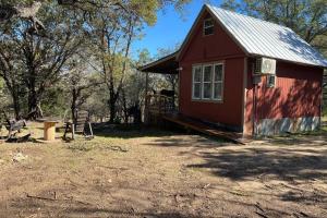 a red house with a table and a bench in front of it at The Cowboy Cabin in Marble Falls