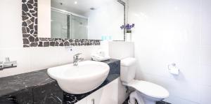 Victoria Square Apartments في غولد كوست: حمام أبيض مع حوض ومرحاض