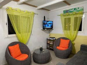 ein Wohnzimmer mit 2 Stühlen und einem TV in der Unterkunft Sunrise in Le Moule