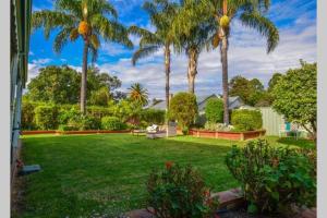 un patio con palmeras y césped verde en Wandew - Echuca Holiday Homes en Echuca