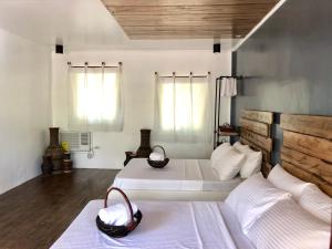 two beds in a room with white walls and wooden floors at PAYAG SUITES in General Luna
