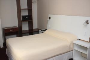 a bedroom with a white bed and a night stand at Hotel Catedral San Rafael in San Rafael +4 photos