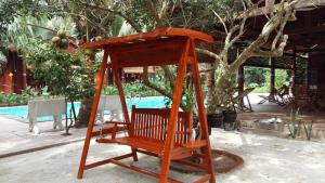 a wooden swing sitting in front of a pool at Coconut Homestay Mỏ Cày Nam Bến Tre in Ben Tre