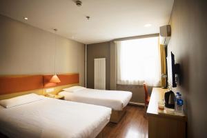 a hotel room with two beds and a television at Home Inn Xi'an South Taihua Road Daming Palace Relics Park in Xi'an