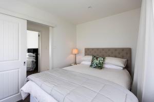 a white bedroom with a large bed with a headboard at Peria Hills Cottage in Matamata