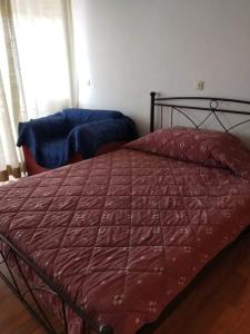uma cama com um edredão vermelho num quarto em Between the Airport and the Harbour em Mitilene