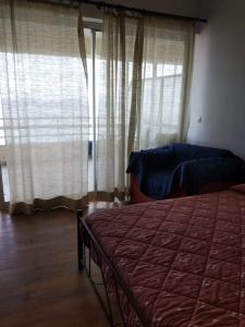 a bedroom with a bed and a window with curtains at Between the Airport and the Harbour in Mytilini
