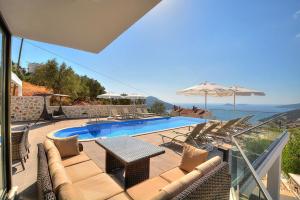 a swimming pool with chairs and a table and umbrella at Villa Ahiska in Kalkan +31 photos