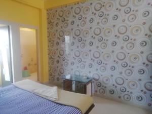 1 dormitorio con 1 cama y una pared con un patrón de remolino en Zeromiles Hotel Prasant en Digha