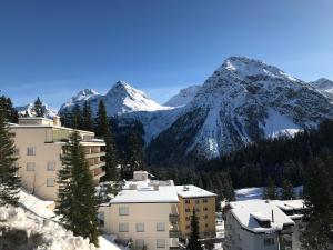 un bâtiment avec une montagne en arrière-plan et de la neige dans l'établissement Casa Irmella 12 - Arosa - alles komplett, à Arosa