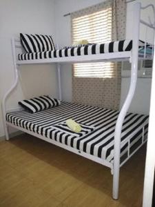 a white bunk bed with black and white stripes at Thirdy's Place Hostel in Legazpi