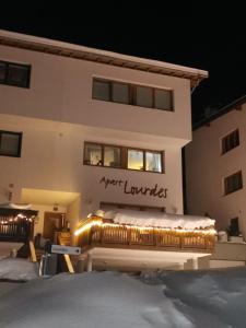 ザーファウスにあるApart Lourdesの夜の雪の中のベンチ付きの建物