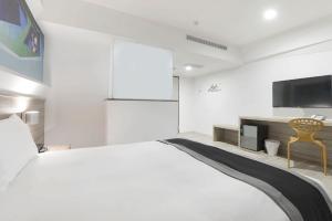 a white bedroom with a large bed and a tv at Trans Inn in Taichung