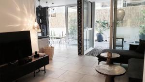a living room with a couch and a tv and a table at Etis garden seafront in Haifa