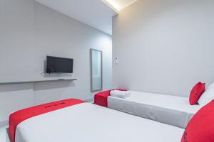 a white room with two beds and a tv at RedDoorz Plus @ Cirebon City Center in Cirebon