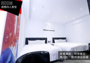 two beds in a room with white sheets and a sign at If Motel In Fashion in Taoyuan