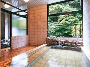 La salle de bains est pourvue d'une piscine et d'une grande fenêtre. dans l'établissement Shima Onsen Ichigekan, à Nakanojo