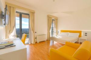 a hotel room with a bed and a couch and window at Hotel Palazzo Bello in Recanati