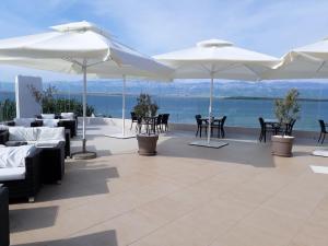 a patio with white umbrellas and tables and chairs at Apartments & Restaurant Condura Croatica Nin-Sabunike in Nin